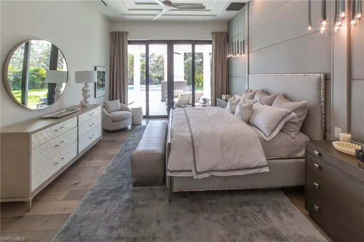 Master suite with a wall of doors overlooking the outdoor fireplace and pool