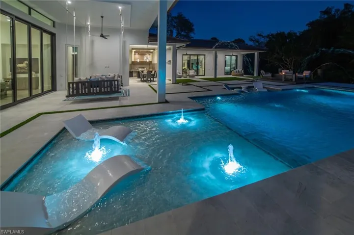 Pool at twilight featuring lots of outdoor living space, pool water features, ceiling fans, and a plenty of under-cover areas