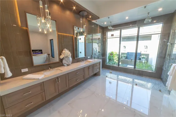 Master Bathroom with an inviting chandelier, oversized vanities, and walls of tile