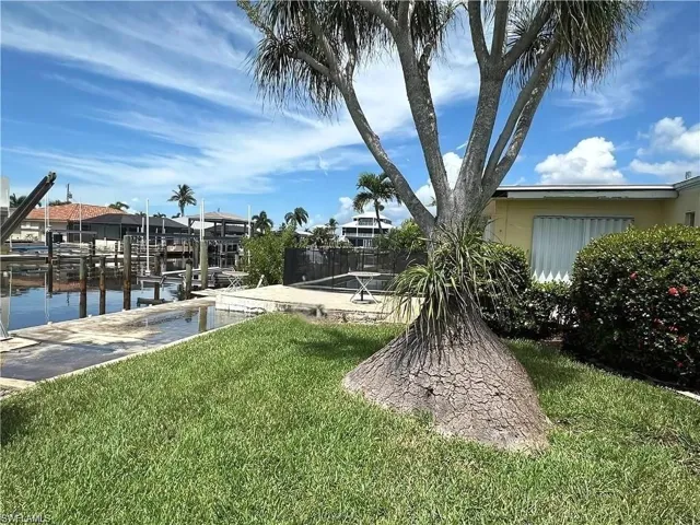 Spacious waterfront yard with lush greenery and private dock access - Virtually Edited Image