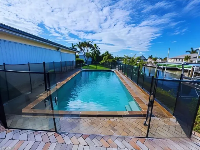 In-ground pool with paver deck and safety fencing, overlooking the canal - Virtually Edited Image