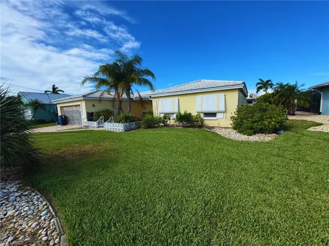 Ranch-style home with tropical landscaping and a wide lawn - Virtually Edited Image