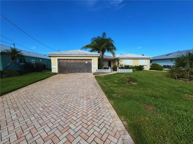 Paver driveway leading to two-car garage with front entry and lawn space - Virtually Edited Image