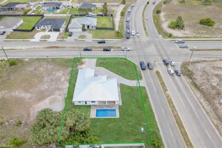 The property features a private swimming pool, a spacious green lawn, and a light-colored roof