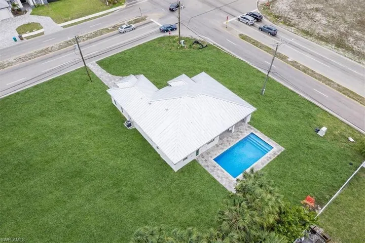 The property features a well-maintained lawn and a private swimming pool with surrounding patio paving.