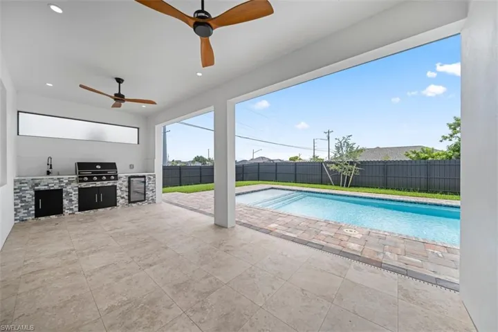 Covered patio featuring an outdoor kitchen with grill, sink, and beverage refrigerator