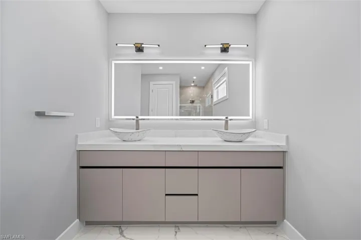 Dual vessel sinks crafted from patterned stone, set upon a neutral-toned vanity with integrated storage