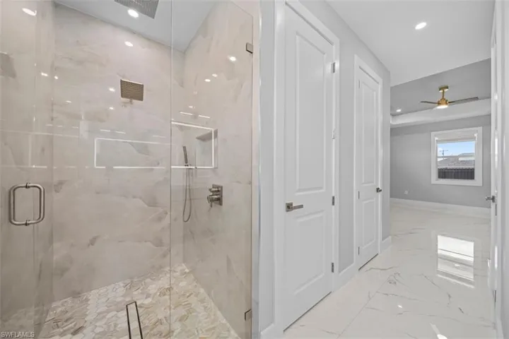Glass-enclosed shower with full-height tile surround, recessed niche, and mosaic tile flooring