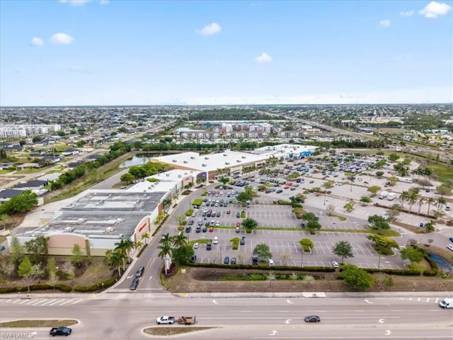 Aerial view showcasing the property's commercial buildings, large parking areas, and convenient proximity to a main road