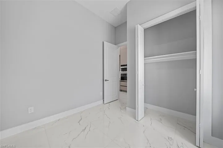 Room featuring white marble-look tile flooring, light gray wall paint, and white baseboards