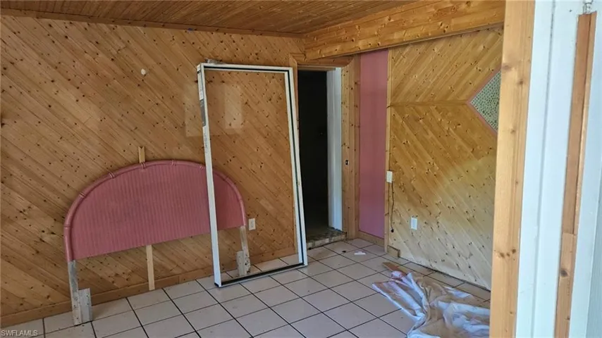 Additional living space with wood walls, tile patterned floors, and wooden ceiling