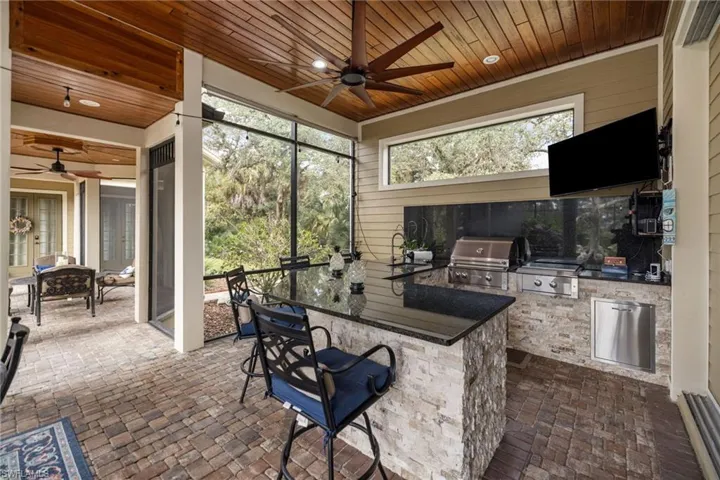 View of patio with ceiling fan, an outdoor kitchen, and a sunroom