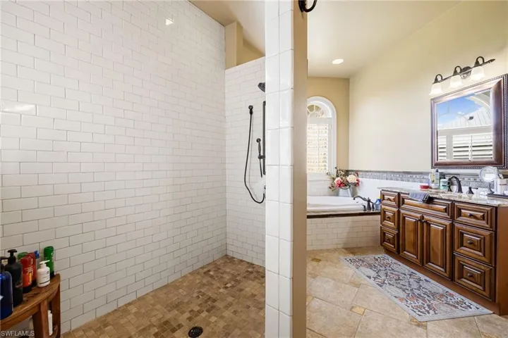 Full bath with a garden tub, vanity, walk in shower, light tile patterned flooring, and recessed lighting