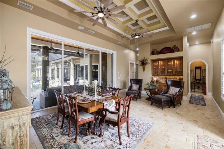 Dining area with coffered ceiling, arched walkways, recessed lighting, ceiling fan, and a raised ceiling