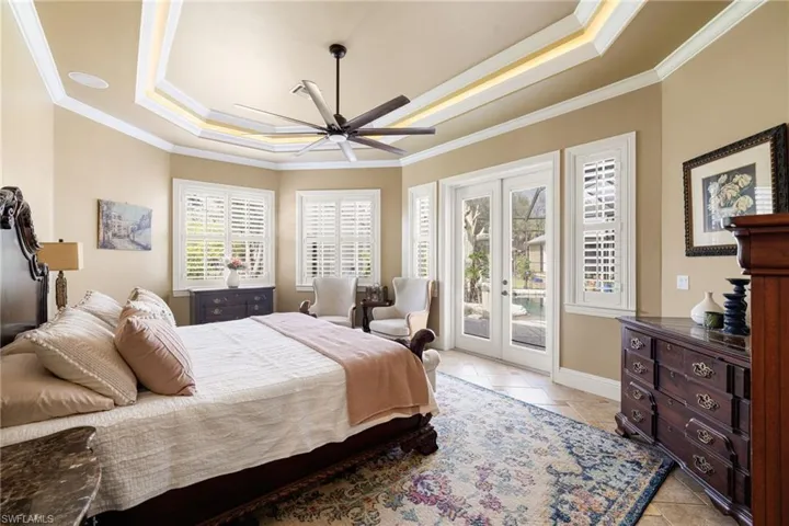 Bedroom with french doors, access to outside, ceiling fan, a raised ceiling, and crown molding