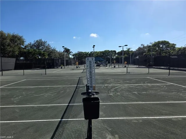 Multiple hard tennis courts with black perimeter fencing