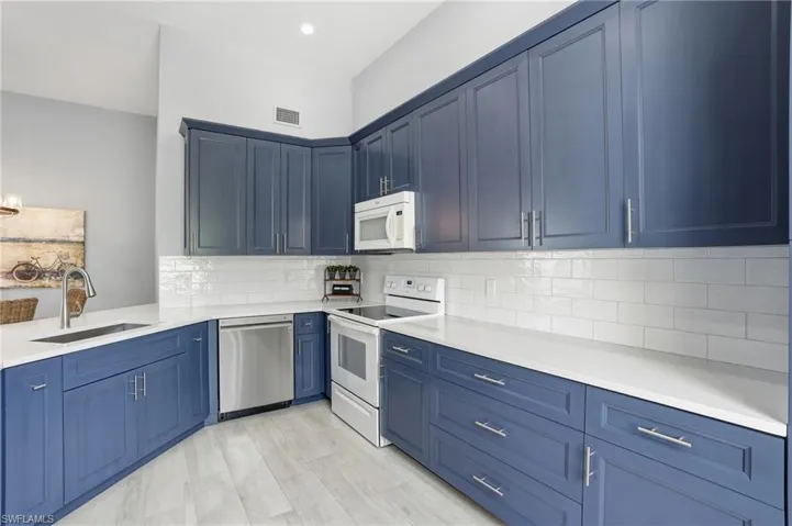 Kitchen featuring blue shaker-style cabinetry, white countertops, and a white subway tile backsplash