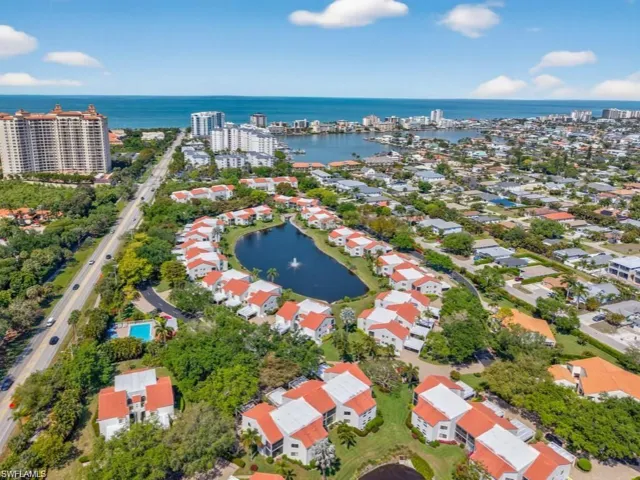 Aerial perspective showcasing a residential community with a central pond and water feature