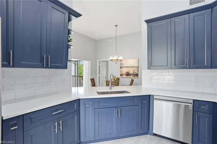 Navy blue cabinetry with brushed nickel hardware, white countertops, a stainless steel sink, a stainless steel dishwasher, and a white subway tile backsplash