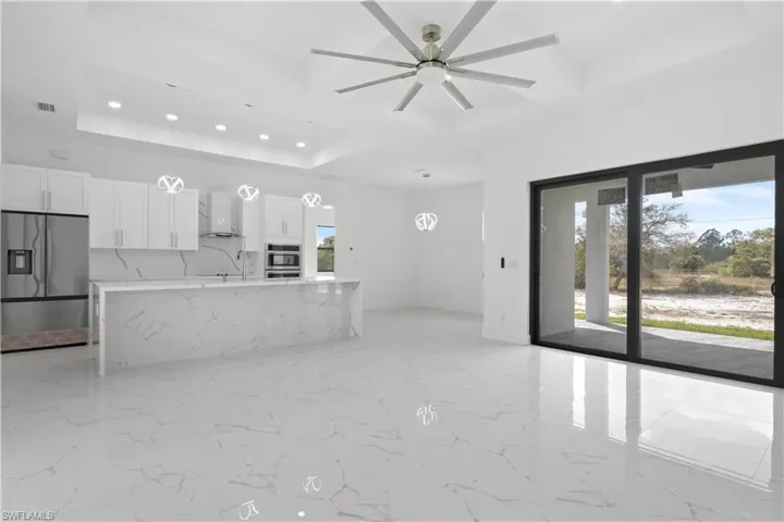 Kitchen featuring visible vents, coffered ceiling, stainless steel fridge with ice dispenser, wall chimney range hood, and white cabinetry