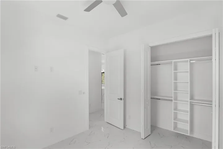 Unfurnished bedroom with marble finish floor, visible vents, and baseboards