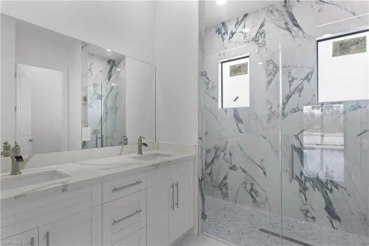 Bathroom featuring marble finish floor, a sink, and a marble finish shower
