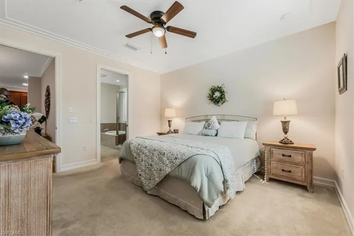 Bedroom featuring crown molding, light carpet, ensuite bath, and ceiling fan