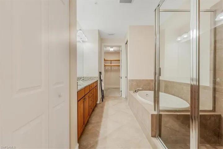 Full bath featuring vanity, a bath, a stall shower, and a walk in closet