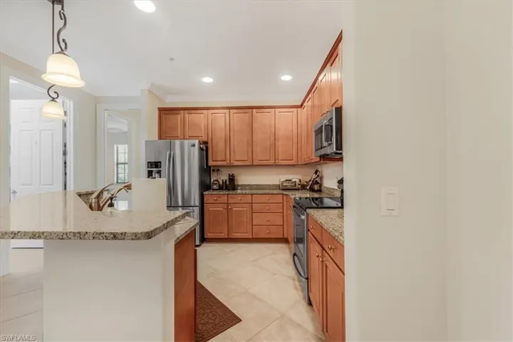 Kitchen featuring stainless steel appliances, decorative light fixtures, recessed lighting, an island with sink, and light tile patterned floors