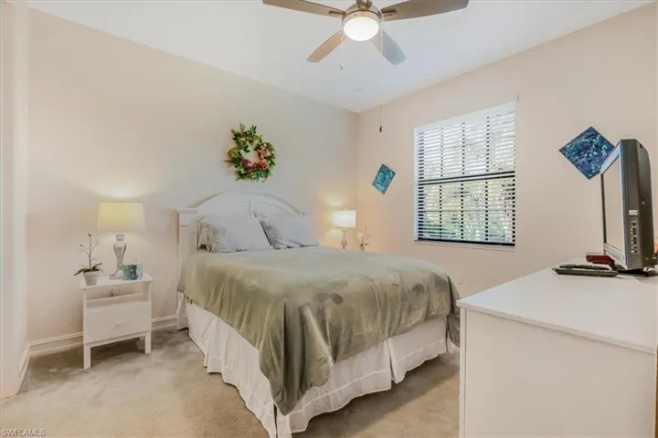 Bedroom with light colored carpet and a ceiling fan