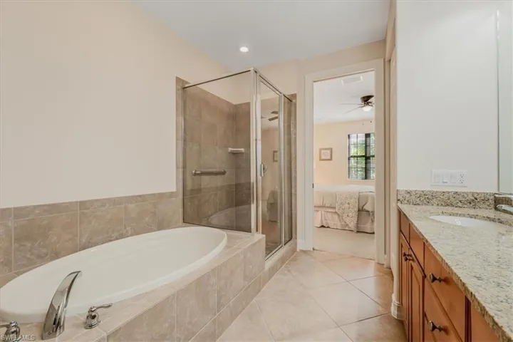 Ensuite bathroom with a bath, vanity, a shower stall, ceiling fan, and tile patterned flooring