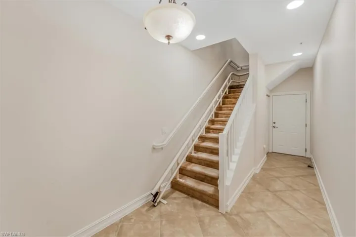 Staircase with tile patterned floors and recessed lighting