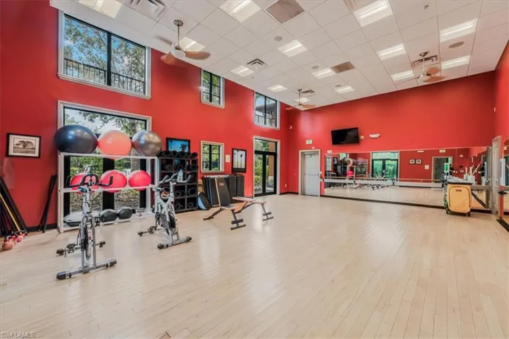 Workout area with a high ceiling, a drop ceiling, wood finished floors, and a ceiling fan