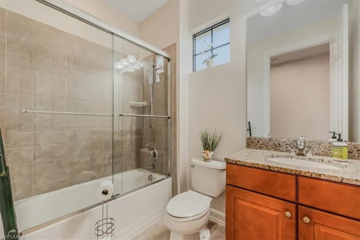 Bathroom featuring vanity and bath / shower combo with glass door