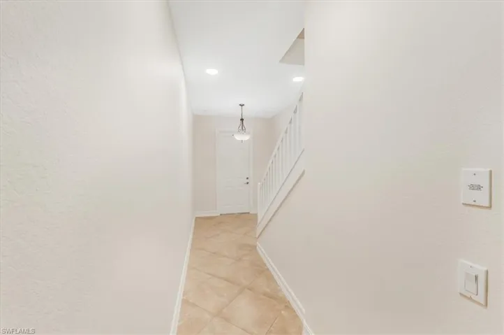 Hall featuring light tile patterned flooring, stairway, and recessed lighting