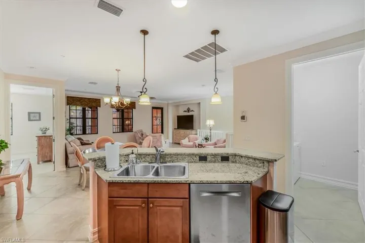 Kitchen with open floor plan, stainless steel dishwasher, a chandelier, light tile patterned floors, and decorative light fixtures