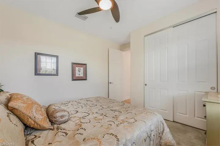 Bedroom with light colored carpet, a closet, and ceiling fan