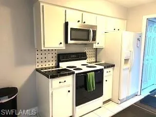 Kitchen with white appliances, white cabinets, and light tile patterned floors