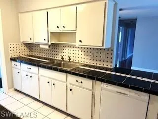 Kitchen with dishwasher, decorative backsplash, white cabinetry, and light tile patterned flooring