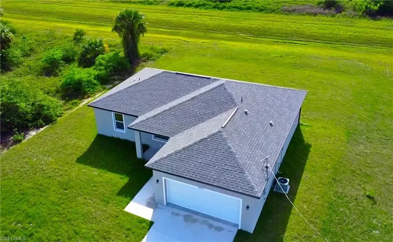 New construction residence featuring a gray stucco exterior, dark shingle roof, and a two-car garage
