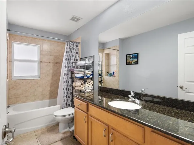 Full bathroom featuring tile patterned floors, vanity, shower / tub combo with curtain, and toilet