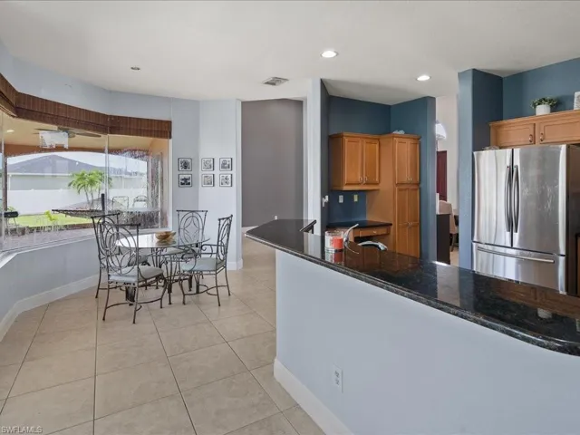 Kitchen with tile  floors, stainless steel fridge, sink, and dark quartzite countertops