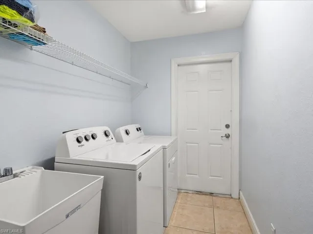 washer and dryer, sink, and tile flooring, access to 2 car garage