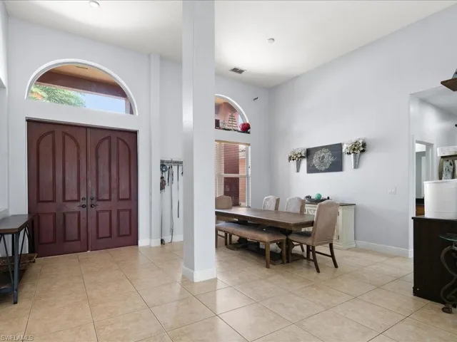 Entrance foyer with light tile floors and a volume ceiling
