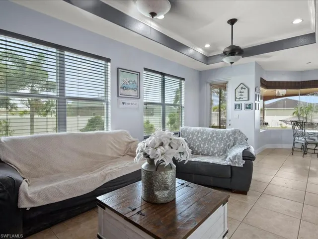 Tiled living room with ceiling fan and a tray ceiling