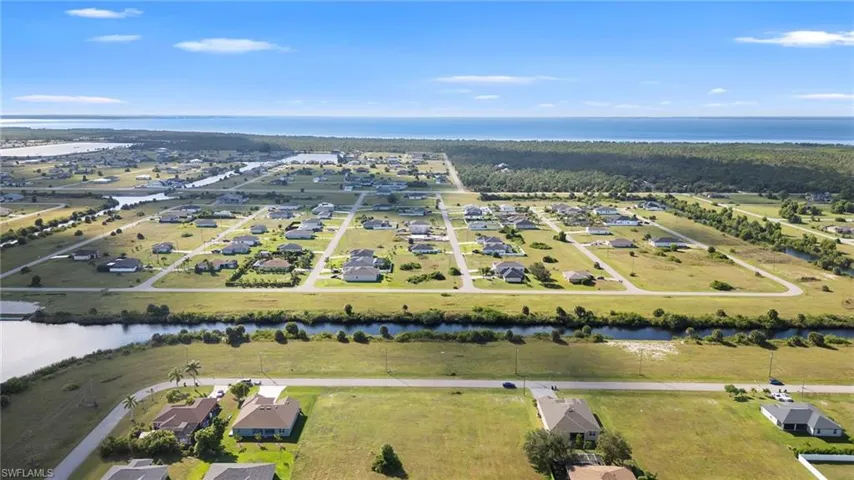 Aerial view of property and surrounding area with a nearby body of water and nearby suburban area