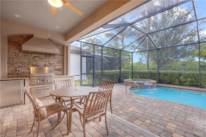 View of pool with ceiling fan, an in ground hot tub, a patio area, a grill, and a lanai