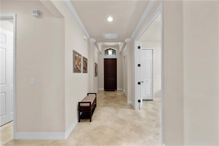 Hallway with ornamental molding and light tile floors