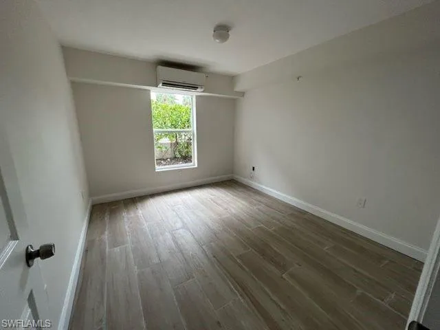 Spare room with a wall mounted air conditioner and hardwood / wood-style flooring