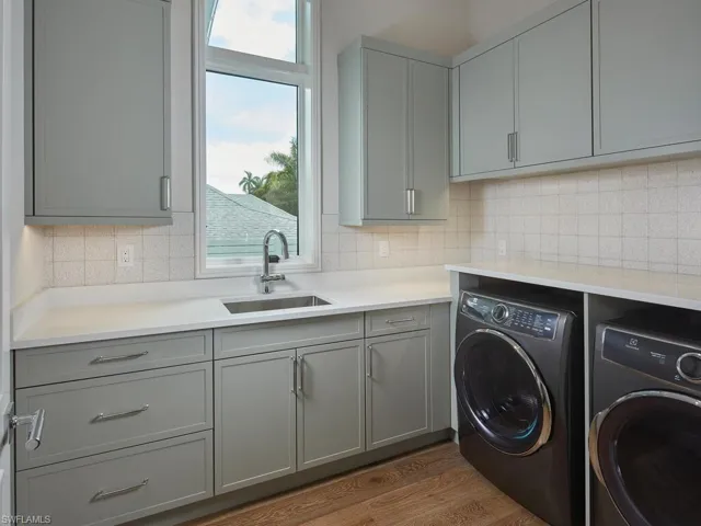 Washroom featuring sink, hardwood / wood-style flooring, separate washer and dryer, and cabinets